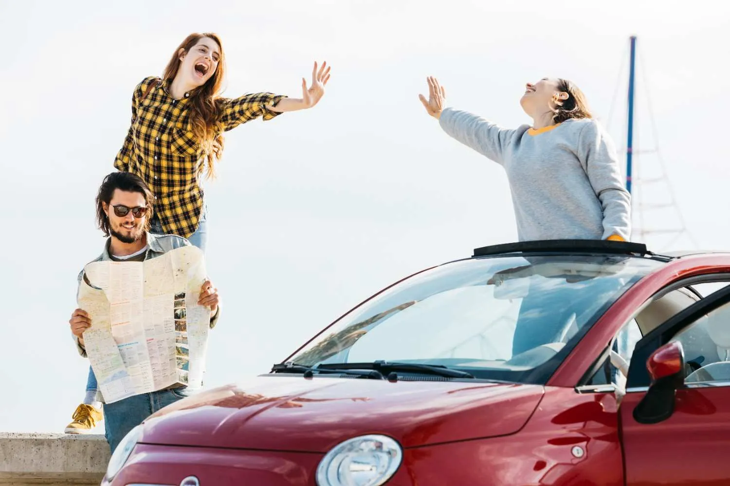 Friends checking a map beside their car on a road trip